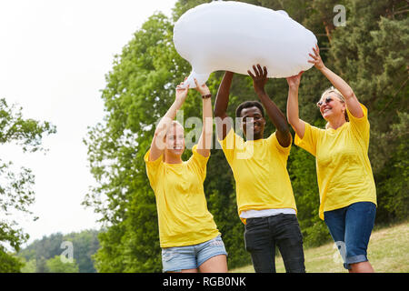 Drei Freiwillige Aktivisten im gelben Hemd mit einem weißen Ballon im Park Stockfoto