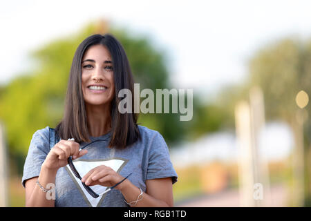 Schönheit ihre Sonnenbrille Holding in einer unscharfen Park. Stockfoto