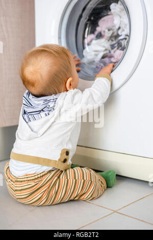 Baby Boy in den Zyklen der Waschmaschine Wäsche interessiert Stockfoto