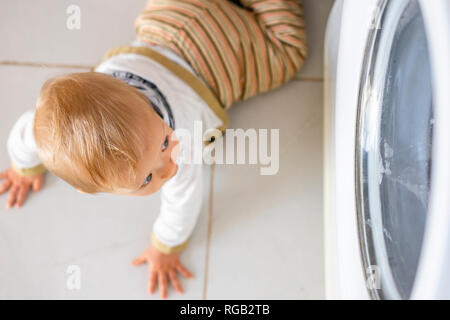 Baby Boy in den Zyklen der Waschmaschine Wäsche interessiert Stockfoto