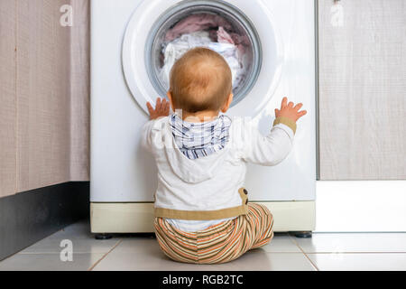 Baby Boy in den Zyklen der Waschmaschine Wäsche interessiert Stockfoto