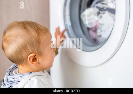 Baby Boy in den Zyklen der Waschmaschine Wäsche interessiert Stockfoto