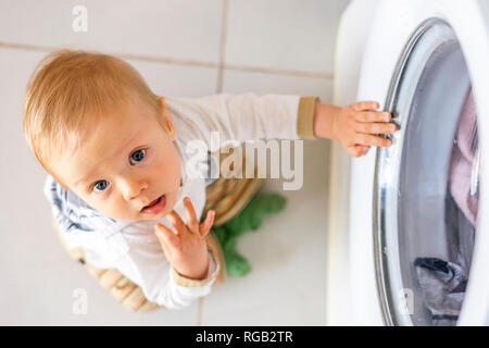 Baby Boy in den Zyklen der Waschmaschine Wäsche interessiert Stockfoto