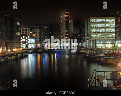 Clarence Dock in Leeds bei Nacht mit hell beleuchteten Gebäuden in das Wasser und die Boote entlang den Seiten günstig wider Stockfoto