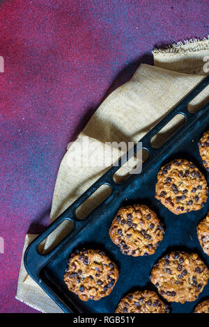 Avena cookies mit Haselnüssen und Chocolate Chips auf ein Backblech legen und mit einem Tuch Stockfoto