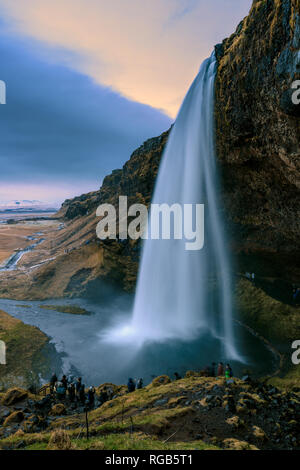 Die legendären Wasserfall Seljalandsfoss in Island. Es gibt unkenntlich touristische Menschen mit Motion Blur im Vordergrund. Stockfoto