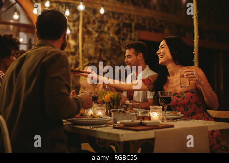 Frau, die Essen mit Freunden zum Abendessen Party im Freien. Millennials in ein gemeinsames Abendessen im Freien. Stockfoto