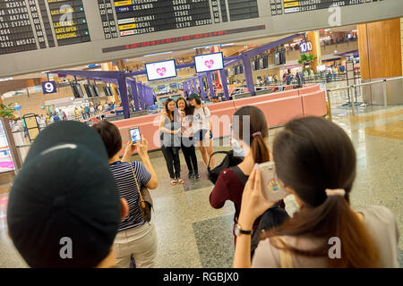 Singapur - ca. August 2016: Frau für phot in Singapur Changi Airport Terminal 2 Abfahrt Halle posieren. Changi Airport ist einer der großen Stockfoto