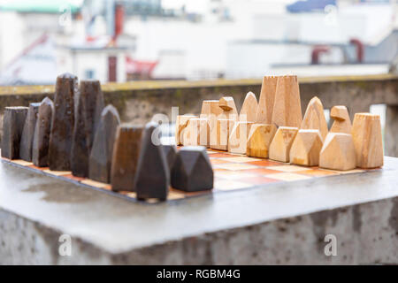 Eine Reihe von Stein handgefertigten Holzmöbeln Schach auf steinernen Tisch in home Outdoor, bevor das Spiel beginnt Stockfoto