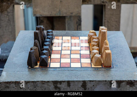 Eine Reihe von Stein handgefertigten Holzmöbeln Schach auf steinernen Tisch in home Outdoor, bevor das Spiel beginnt Stockfoto