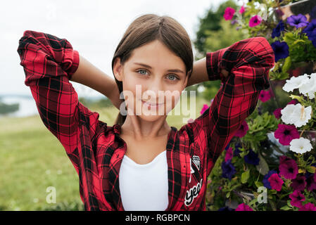 Mädchen Teenager in ein rotes Hemd, im Sommer im Park glättet das Haar, Outdoor Recreation, Nahaufnahme Porträt. Stockfoto
