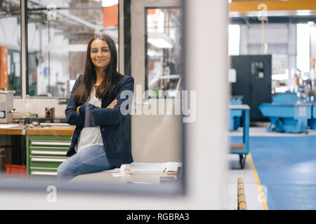 Selbstbewusste Frau sitzen in High Tech Unternehmen, stehend in der factory Workshop mit gekreuzten Armen Stockfoto