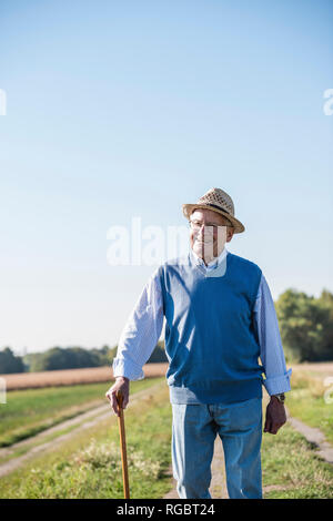 Älterer Mann mit einem Stock, zu Fuß in die Felder Stockfoto