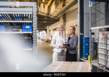 Zwei Frauen mit Tablet in der Lagerhalle Stockfoto