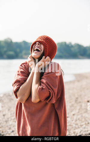 Unbeschwerte junge Frau trägt Wooly hat am Flußufer Stockfoto