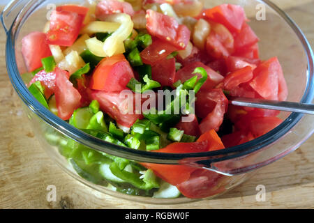 Vegetarische Salat aus geschnittenem Gemüse in Runde transparente Schüssel auf braune Holztisch closeup Vorderansicht Stockfoto