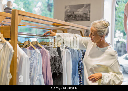 Ältere Frau Einkaufsmöglichkeiten für Kleidung in einer Boutique Stockfoto