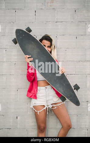 Porträt einer jungen Frau mit ihren langen, vor einer Wand Stockfoto