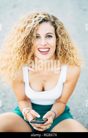 Portrait von Lachen blonde junge Frau mit Handy Stockfoto