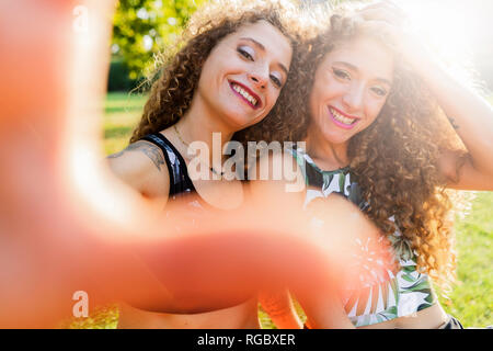 Portrait von Lachen Zwillingsschwestern unter selfie in einem Park Stockfoto