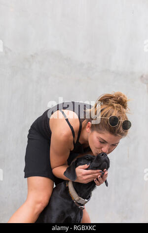 Junge Frau, die ihrem Hund küssen Stockfoto