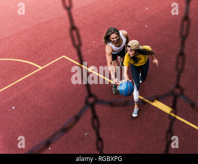 Junger Mann und Frau spielen Basketball auf Basketball Boden Stockfoto