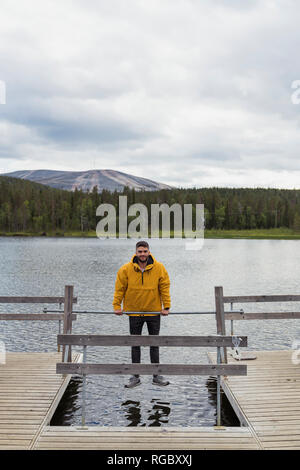 Finnland, Lappland, mann Balancing auf die Stange am Steg über einem See Stockfoto