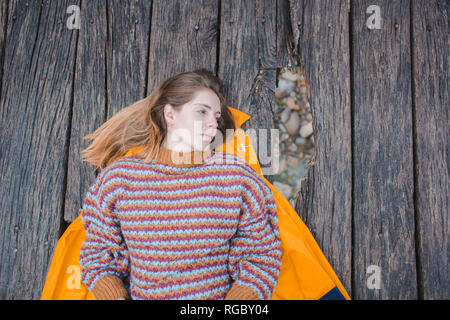Ernsthafte junge Frau liegt auf der Promenade entfernt suchen Stockfoto