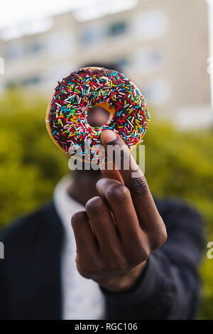 Junge schwarze Mann hält eine Schokolade cookie Stockfoto