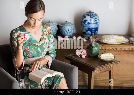 Junge Frau trinkt Tee beim Lesen eines Buches zu Hause Stockfoto