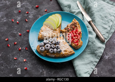 Scheiben Brot mit verschiedenen Toppings auf Platte Stockfoto