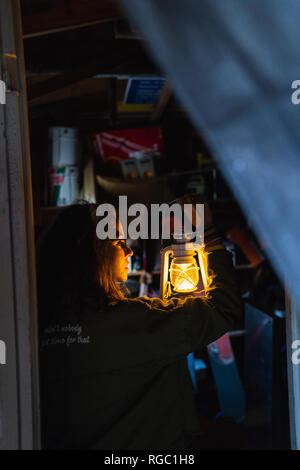 Junge Frau mit Sturm Laterne in einer dunklen Kammer Stockfoto
