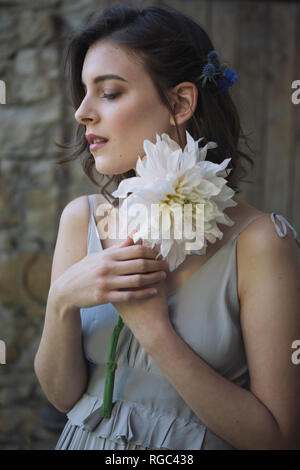 Junge Frau trägt graues Kleid Holding eine Blume Stockfoto