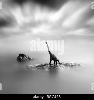 Ein Spielzeug Dinosaurier auf einem Stein, Schwarze und Weiße, lange Belichtung Stockfoto