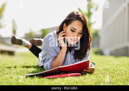 Portrait von Studenten liegen auf dem Rasen lesen Ihre Notizen Stockfoto