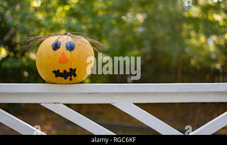 Ein tolles halloween Hintergrund Foto von einem Kürbis mit Gesicht auf es auf ein Geländer lackiert. Stockfoto