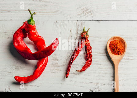 Frisches, getrocknetes und gemahlener roter Chili Pfeffer über farbige Holz- Hintergrund. Stockfoto