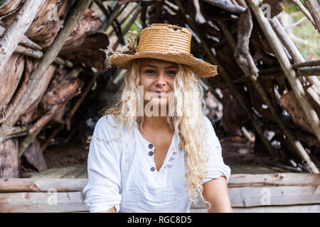 Portrait von lächelnden jungen Frau mit strohhut an der hölzernen Unterstand Stockfoto