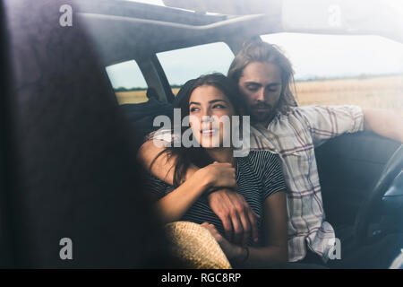 Liebevolle junge Paar im Auto Stockfoto