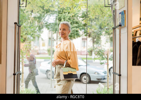 Lächelnd senior Frau entlang eine Boutique Stockfoto