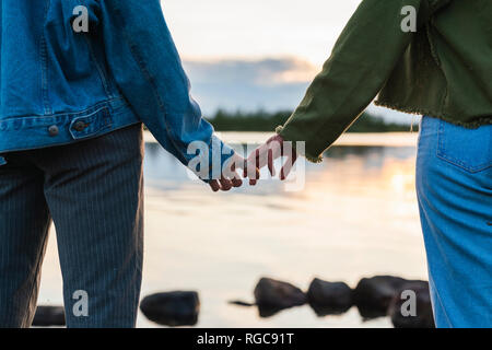 Finnland, Lappland, close-up von zwei jungen Frauen Hand in Hand am Seeufer in der Dämmerung Stockfoto