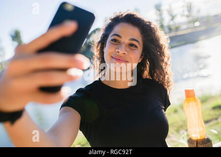 Sportliche junge Frau, eine selfie am Flußufer Stockfoto