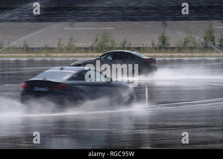 Zwei Autos fahren auf nasser Fahrbahn auf der Rennstrecke Stockfoto