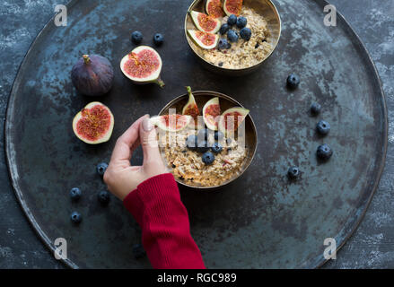 Woman's Hand garnieren Schüssel Haferbrei mit in Scheiben geschnittenen Abb. Stockfoto