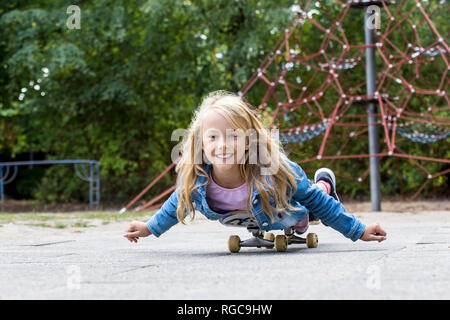 Portrait von lächelnden blonde Mädchen mit Skateboard auf einem Spielplatz Stockfoto