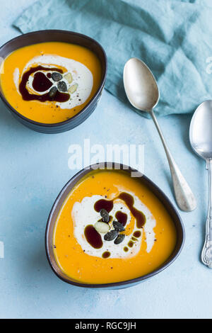 Zwei Schalen mit hausgemachten Hokkaido Kürbis Suppe, garniert mit Sahne, Kürbiskernöl und Kürbiskerne Stockfoto