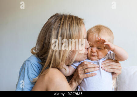 Mutter küssen ihre Grimassen baby girl Stockfoto