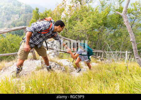 Italien, Massa, Menschen zu helfen, eine junge Frau einen Schritt beim Wandern in die Apuanischen Berge klettern Stockfoto