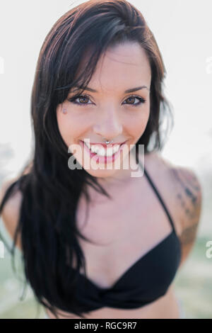 Portrait von lächelnden jungen Frau mit nasenpiercing am Meer Stockfoto
