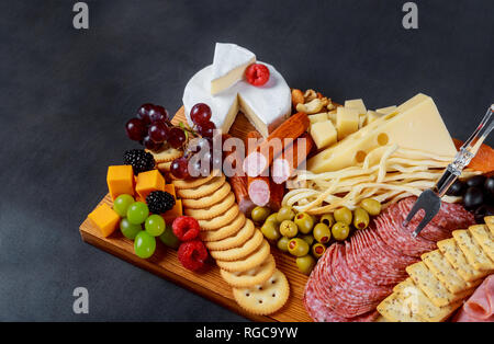 Snack mit verschiedenen Fleisch, Käse, Cracker, grüne Oliven, Nüsse und Beeren über holztisch Hintergrund Stockfoto